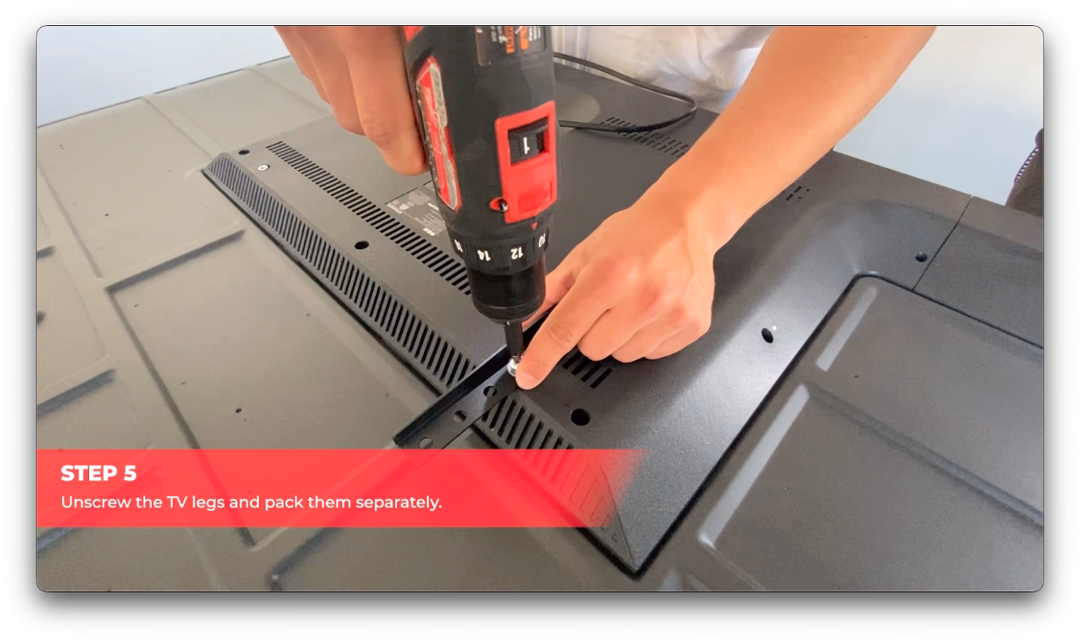 Cactus Moving worker unscrewing TV legs with a power drill for safe packing.