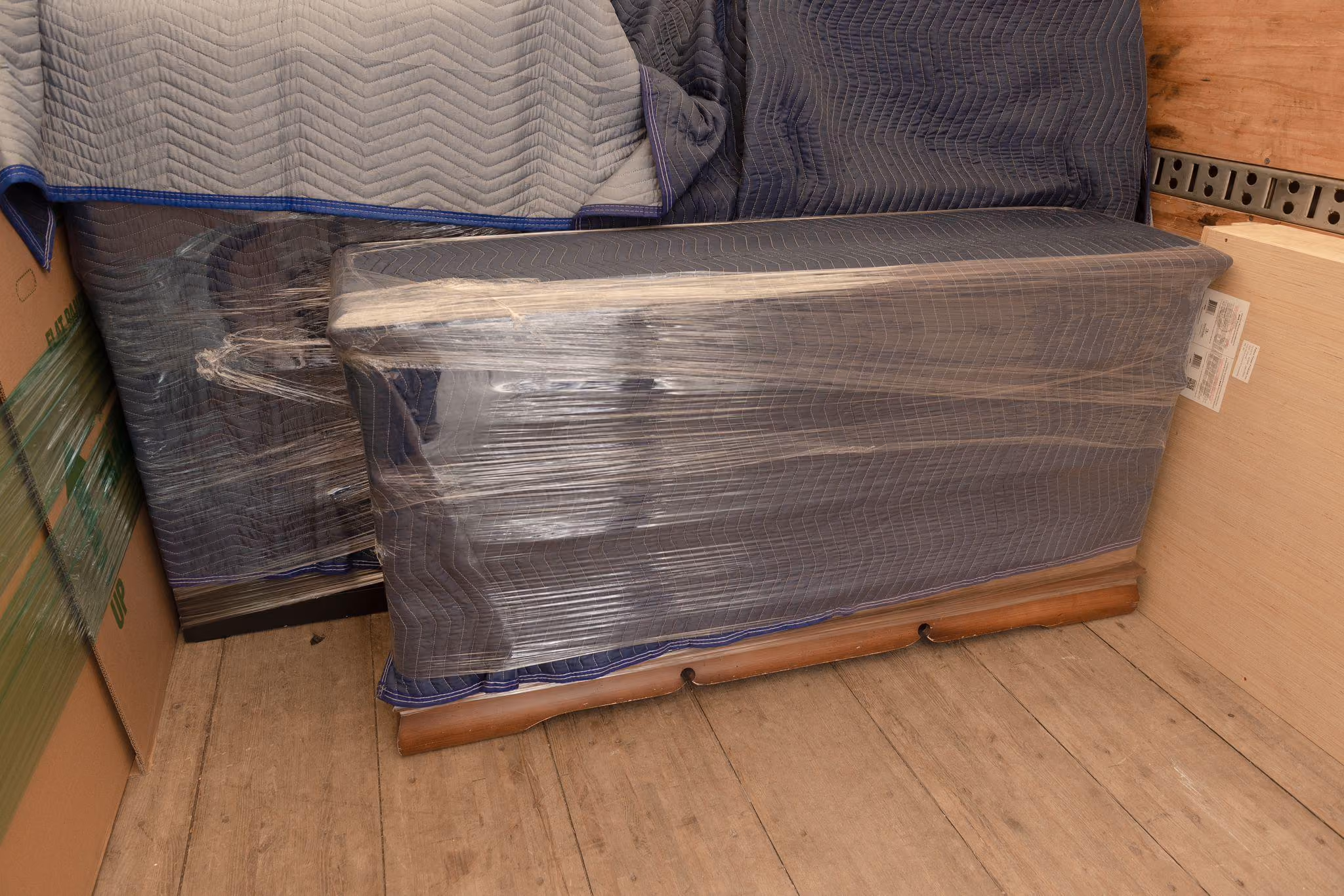 A wooden dresser wrapped in heavy duty moving blanket and stretch wrap