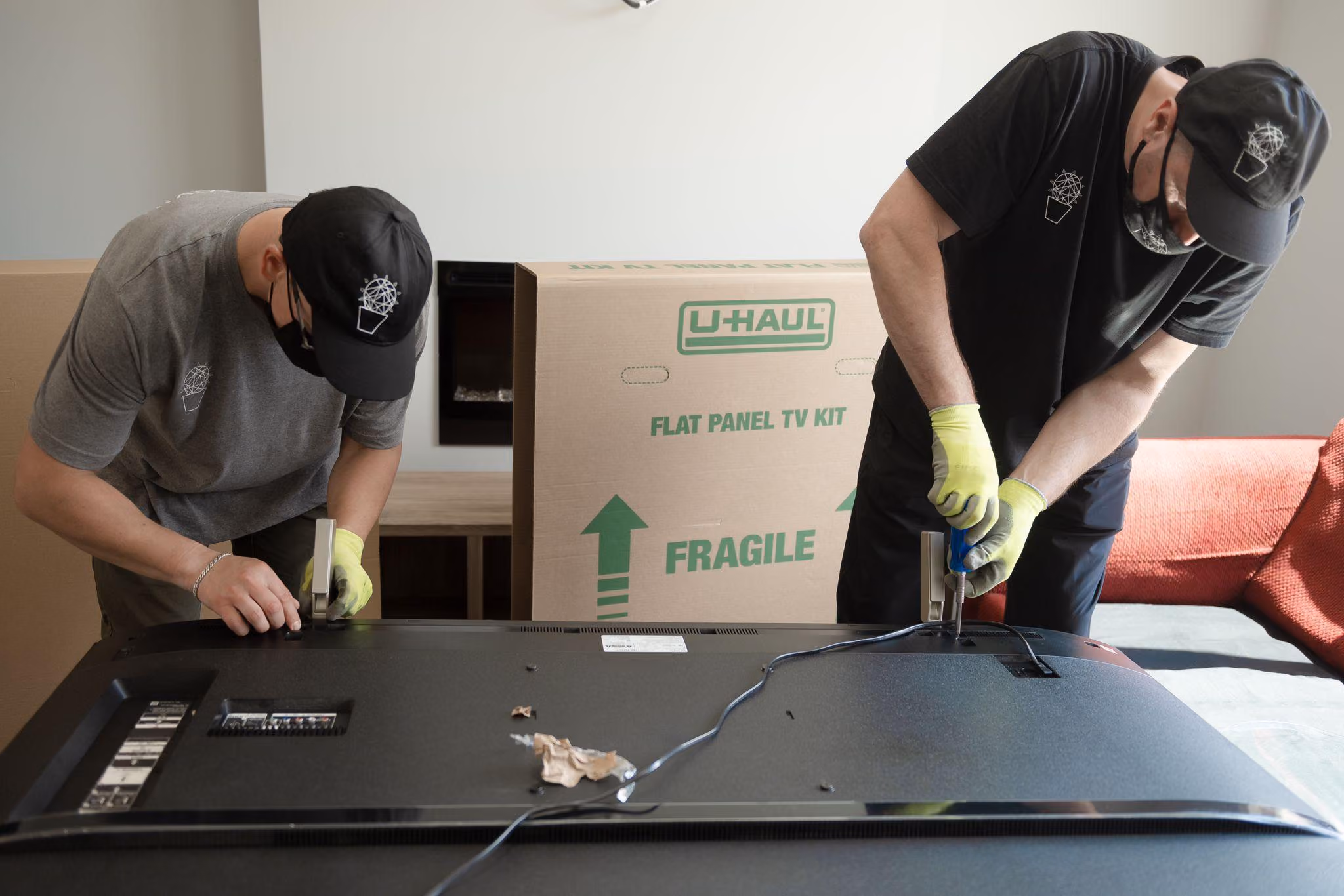 Movers unscrew TV legs to prepare for packing in TV box